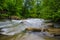 ND filter photo. Milk water flow rapid stream. Caucasus rocky mountain river in forest.