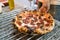 Neapolitan pizza style: close-up chef hand cutting chorizo sausage pizza on the pizza cooling rack on the kitchen counter.