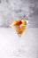 Neapolitan Rum baba or baba au rum in a martini glass with a cocktail cherry on a gray background. Small yeast cakes.