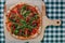 Neapolitan spicy pizza with ham, cheese, arugula, basil, tomatoes, pepperoni pepper sprayed with cheese on a wooden board on a