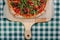 Neapolitan spicy pizza with ham, cheese, arugula, basil, tomatoes, pepperoni pepper sprayed with cheese on a wooden board on a