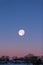 Near Full Moon Rising over Houses in Red and Blue Winter Sky