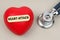 Near the stethoscope lies a heart on which a sticker is pasted with the inscription - HEART ATTACK