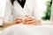 Neat female hands of a massage therapist-cosmetologist do massage with a gouache scraper made of jade in the shape of a