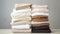 a neat stack of folded fabrics in shades from white to dark brown on a surface against a grey background
