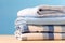 neat stack of white and blue shirts, along with other garments, hanging on table. Image exudes sense of order and style, as shirts