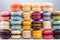 Neatly stacked vibrant macarons in multiple flavors and colors against a neutral backdrop.