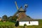 Nebel, Amrum, Germany - June 1st, 2016 - Historic thatched-roof windmill with bright yellow sails and small whitewashed museum bui