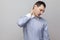 Neck pain. Portrait of handsome bristle businessman in classic light blue shirt standing holding his painful neck and feeling