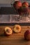 Nectarine halves on chopping board with apples in the background.