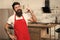 Need culinary inspiration. How to turn cooking at home into habit. Man bearded hipster red apron stand in kitchen