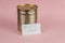 Need food. Business card with handwritten text and canned food against a pink background. Gold-colored tin. Concept of helping the