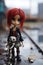 Neglected and lonely lifelike doll with bright red dyed hair in abandoned city backstreets - generative AI