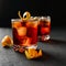 Negroni alcoholic cocktail in two glasses decorated with orange peel with ice cubes on a dark table