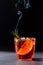 Negroni cocktail with smoking rosemary and orange garnish on black background