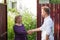 Neighbors discuss the news, standing at the fence. An elderly woman talking with a young man