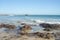 Nelson Mandela Bay beach with rocks looking towards harbour cranes