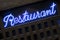 Neon blue restaurant sign lit up at night closeup