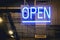 Neon light color blue Open sign on a glass window for business front of shop