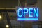 Neon light color blue Open sign on a glass window for business front of shop