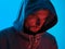 Neon light portrait of serious man in hoody.