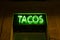 Neon panel with the word Tacos written in green