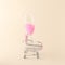 Neon pink champagne drink in a champagne glass set in a shopping cart on a cream background.