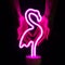 Neon pink flamingo LED lamp in female hands on a black