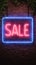 Neon sale sign on brick wall, vibrant urban advertising