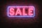 Neon sale sign on brick wall, vibrant urban advertising
