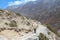 Nepalese sherpa porter walks on footpath carrying heavy bags