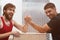 Nerd hipster is arm wrestling with a muscular guy in gym