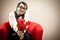 Nerd man wait his love on red armchair with flower gift