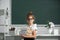 Nerd school girl in glasses with books on blackboard. School child in glasses hold book with serious expression against