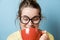 Nerd young woman with a red mug on a blue background. Studio shot