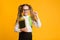 Nerdy School Girl Holding Books Gesturing Need More, Yellow Background