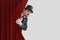 Nervous actor or illusionist is hiding behind red curtain in theater