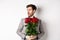 Nervous boyfriend waiting for his date on valentines day, looking left amazed, holding bouquet of red roses, standing in