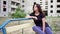 Nervous brunette girl is sitting near high building