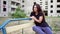 Nervous brunette girl is sitting near high building