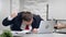 Nervous business man during sudden computer failure sitting on desk in front of broken pc.