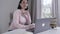 Nervous Caucasian young woman looking at screen, hearing something, closing laptop and leaving. Brunette wife or mother