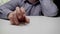 A nervous clerk or businessman is tapping his fingers on the table. Hand of a man in a gray shirt is knocking on the