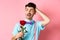 Nervous man waiting for his date on Valentines day, holding red rose and looking confused sideways, scratching head