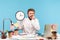 Nervous unhappy man office worker biting nails holding big wall clock, sitting at workplace all covered with sticky notes,