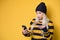 Nervous woman holding mobile phone, model wearing woolen cap and sweater, isolated on yellow background. No Wi-fi concept. Bad