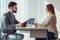 Nervous woman looking at manager reading her resume during a job interview at office