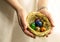 Nest with eggs painted in different colors lie in the palm of the hand