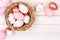 Nest with rose gold, pink and white Easter Eggs against white wood