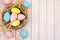 Nest side border with pink, yellow & blue Easter Eggs against white wood